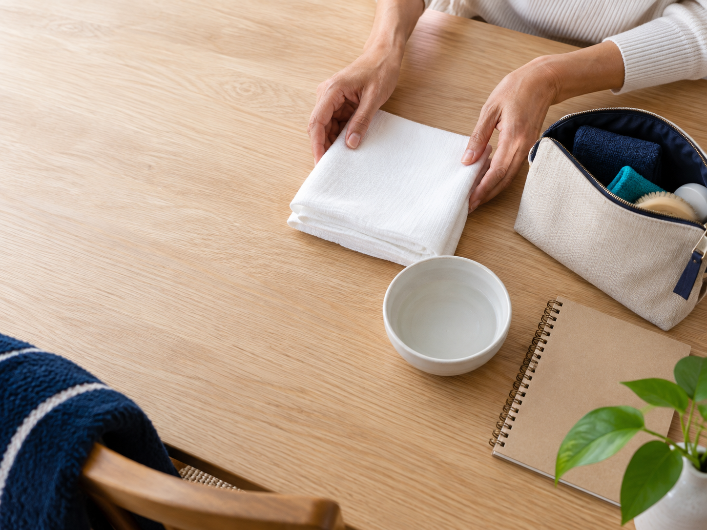 Hands arranging a clean cloth, water bowl, and storage pouch for a care routine